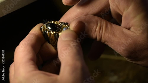 A jeweler is fitting the gem to a gold ring.