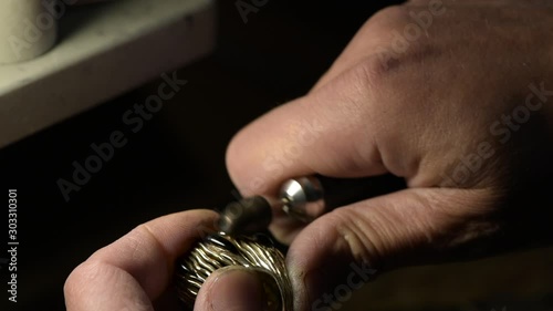 A jeweler is polishing a gold ring decorated with precious stones.