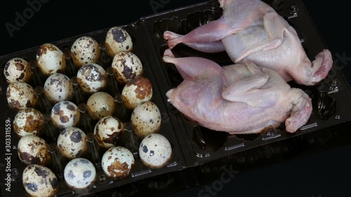 Fresh meat of quail in a plastic brown tray next to the quail eggs on a black background photo