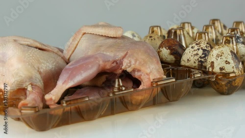 Fresh meat of quail in a plastic brown tray next to the quail eggs on a white background rotate photo