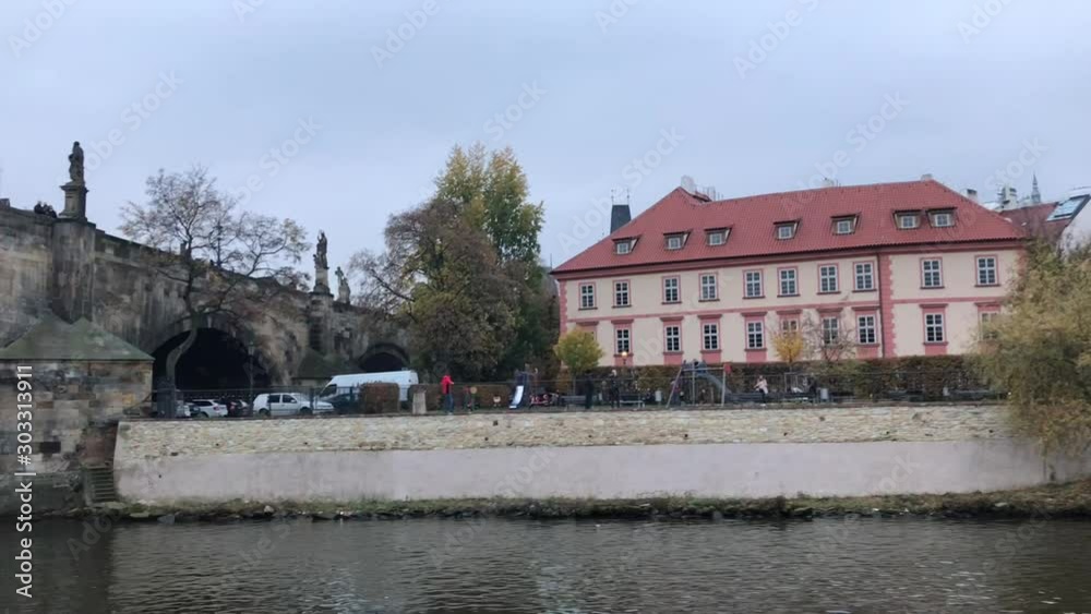 Passing Charles bridge on Vltava river cruise and enjoying Prague bars and cafes with view outdoor heaters on riverbank in November Passing Charles bridge on Vltava river cruise and enjoying Prague bars and cafes with view outdoor heaters on riverbank in November
