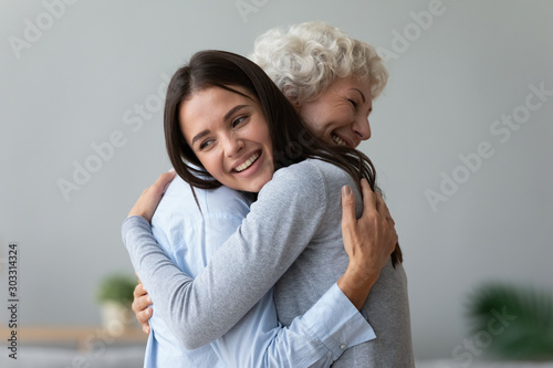 Happy young granddaughter embracing hugging old retired grandmother cuddling photo