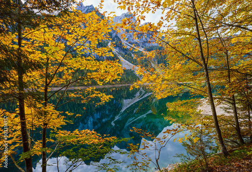 Peaceful autumn Alps mountain lake with clear transparent water and reflections. Gosauseen or Vorderer Gosausee lake, Upper Austria. Dachstein summit and glacier in far.