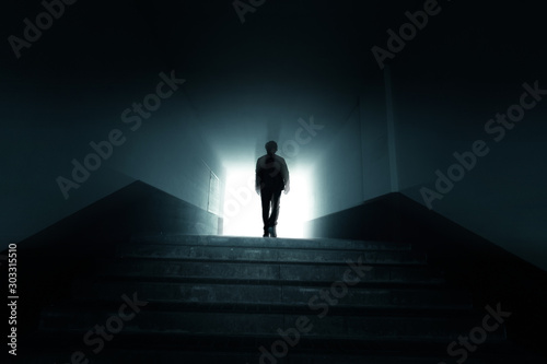 Man walking to the light in the dark tunnel.