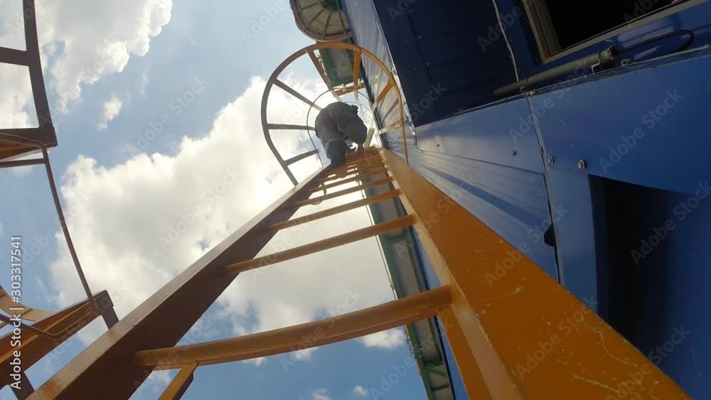 Worker to climbing on the vertical ladder in petroleum refinery plant
