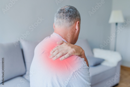 Man grimaces at the pain in his shoulder