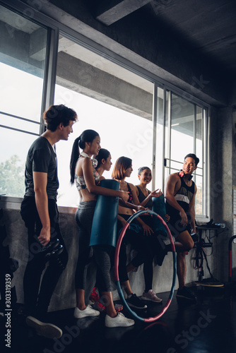 Group of young asian people in sportswear talking after a workout in gym