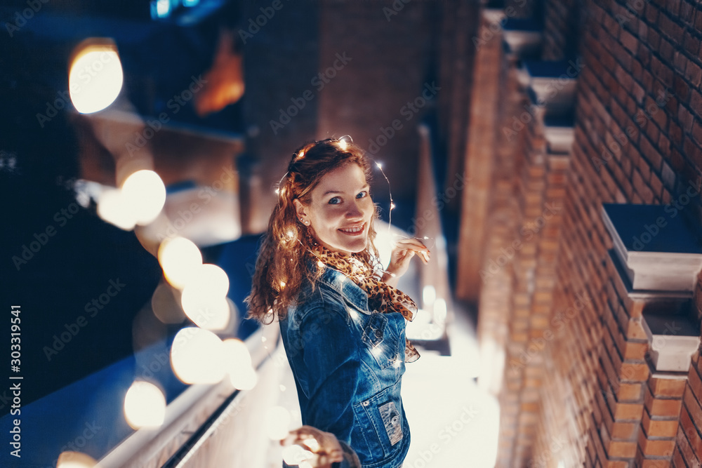 Happy young woman playing with fairy lights outdoors - obrazy, fototapety, plakaty 