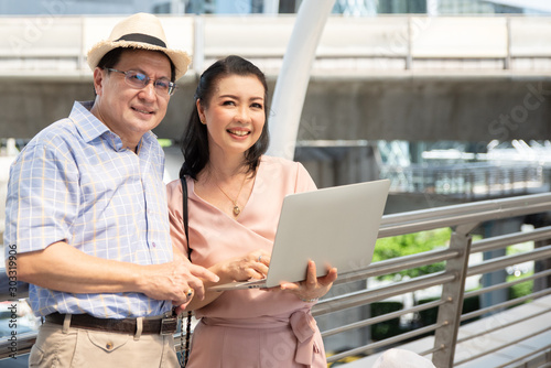 Couple Using Laptop While Standing On Bridge In City © ic36006