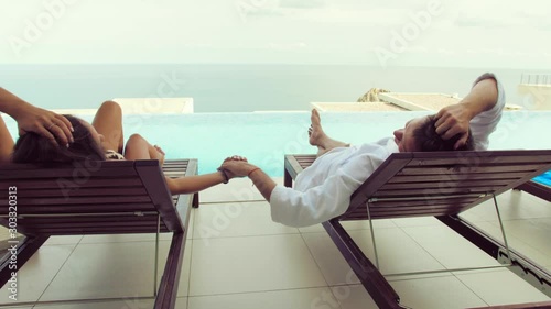 young couple in a hotel by the sea, relaxing by the pool