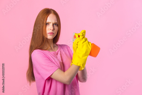 beautiful young woman with red hair in yellow rubber gloves on a pink background
