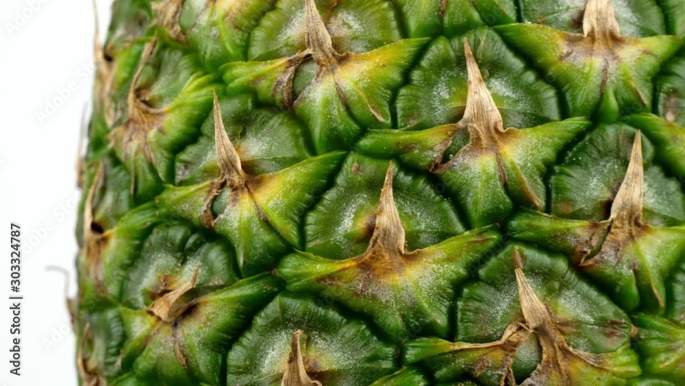 Extreme close up view of a ripe pineapple as it rotates slowly in front of a white studio backdrop Extreme close up view of a ripe pineapple as it rotates slowly in front of a white studio backdrop