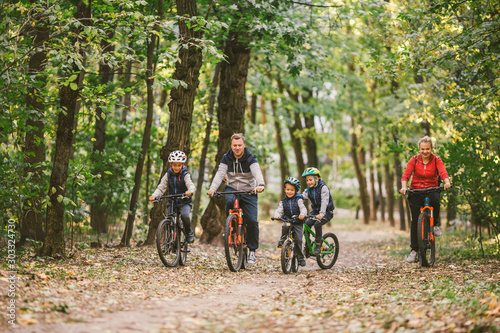 Fényképezés parents and kids cycling on forest trail