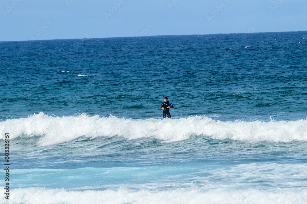 Hispanic Brunette Man Catching Waves On Las Americas Beach. April 11, 2019. Santa Cruz De Tenerife Spain Africa. Travel Tourism Street Photography. Hispanic Brunette Man Catching Waves On Las Americas Beach. April 11, 2019. Santa Cruz De Tenerife Spain Africa. Travel Tourism Street Photography.