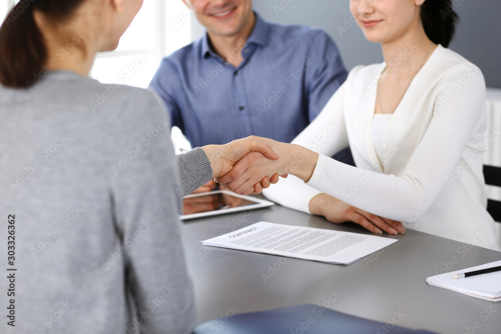 Group of business people shaking hands after discussing questions at meeting in modern office. Handshake close-up. Teamwork, partnership and agreement in business concept Group of business people shaking hands after discussing questions at meeting in modern office. Handshake close-up. Teamwork, partnership and agreement in business concept