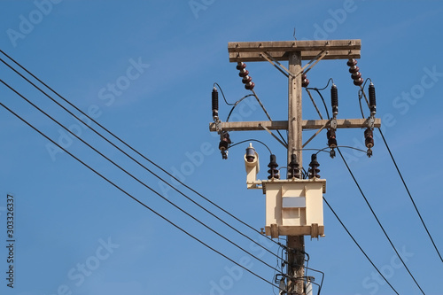 Transformers and electric wire for electrical energy conversion on high voltage poles with blue sky.