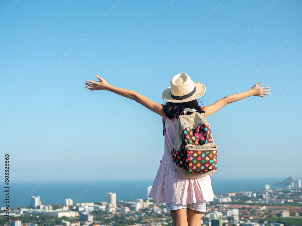 Back of girl raising hands on the top of city view, lifestyle concept.
