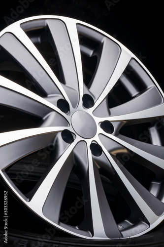 car alloy wheel close up, beautiful design of smooth curved spokes, matte gray color, on dark black background