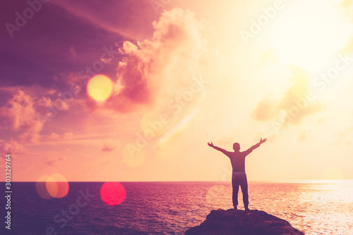 Copy space of happy man hand raise on top mountain at tropical beach and sunset sky abstract background.