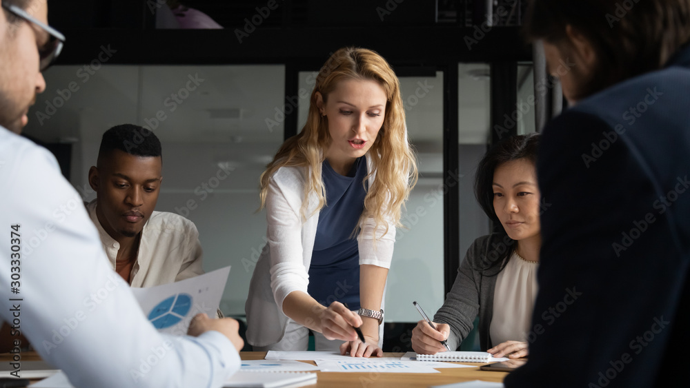 Young businesswoman explaining research results in graphs to colleagues.