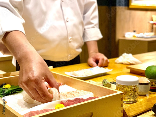 	 Closeup of chef hands preparing japanese food. Japanese Omakase Chef making sushi at restaurant. chef serving traditional japanese sushi with gold served on a stone plate.