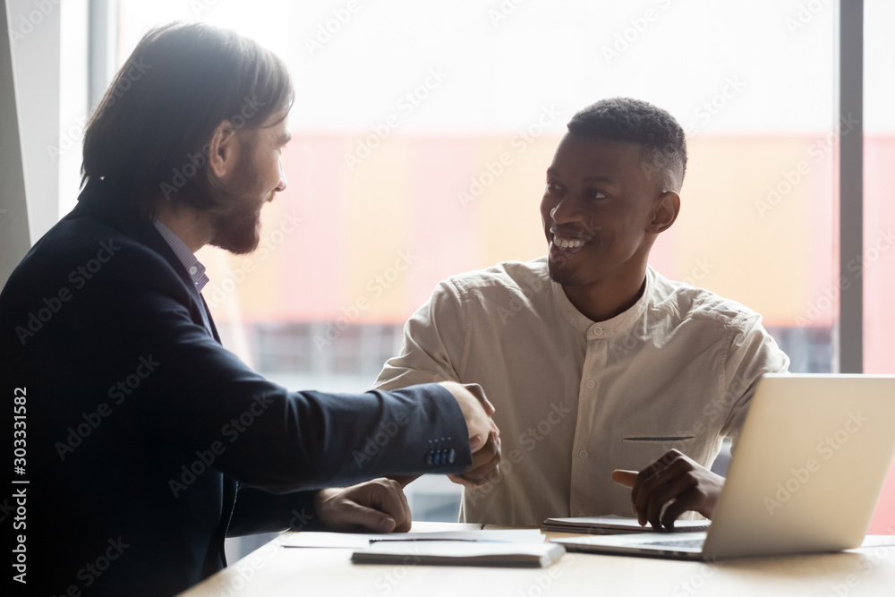 HR manager shaking hands with happy african american employee.
