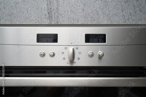Metallic oven and its control panel with displays for setting the temperature and timer, close-up