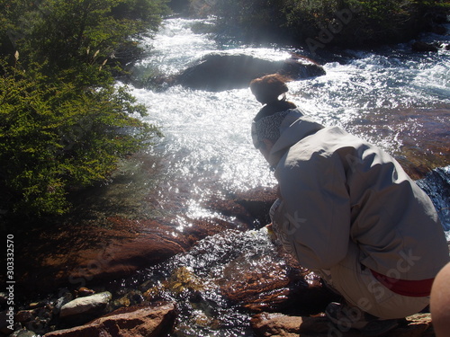 Tableau sur toile A woman hiker staring at a beautiful and clean stream flowing from the mountain,