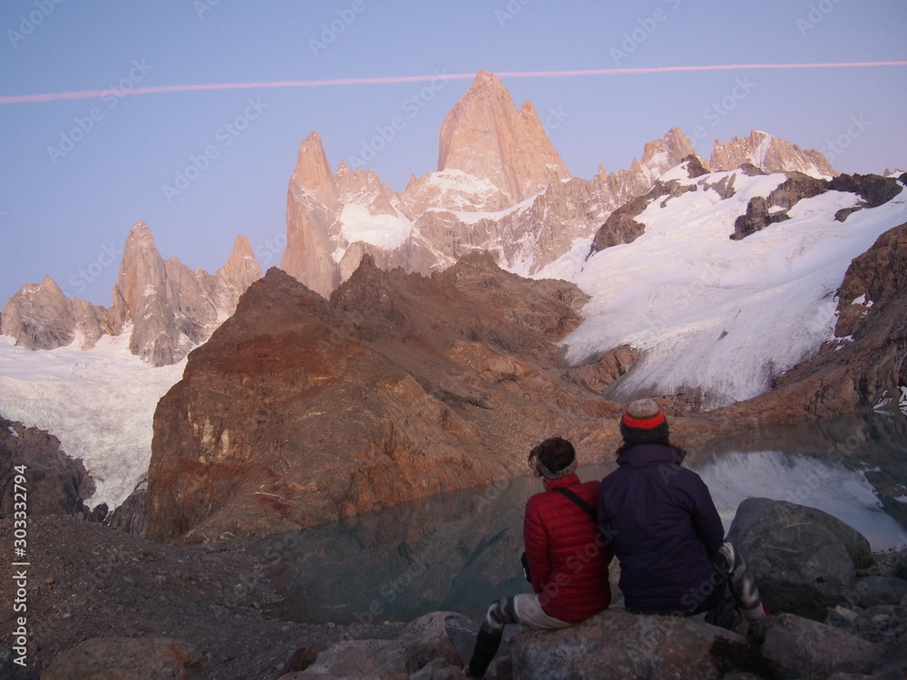 A couple of hikers gazing at Mount Fitz Roy that begins to be tinted red by the sunrise, Precious scenery created by nature, Los Glaciares National Park near El Chalten, Patagonia, Argentina