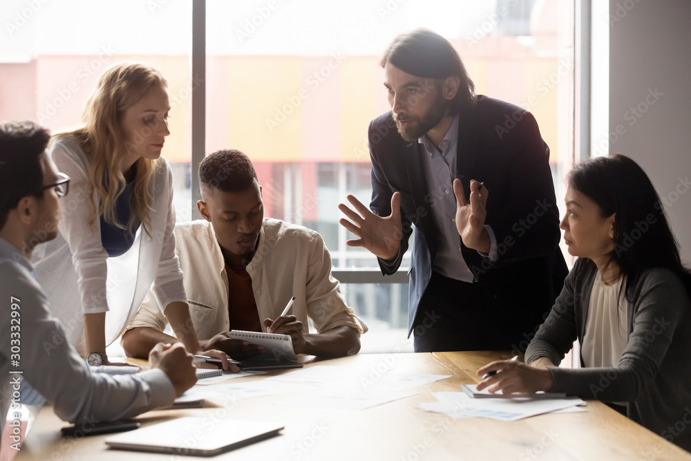 Ταπετσαρία Serious young businessman leaning over table, explaining ideas to teammates
