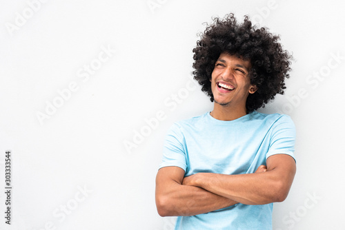 smiling young man with afro hair and arms crossed smiling by white background photo