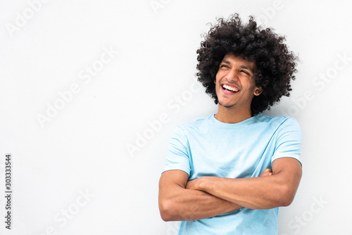 smiling young man with afro hair and arms crossed smiling by white background