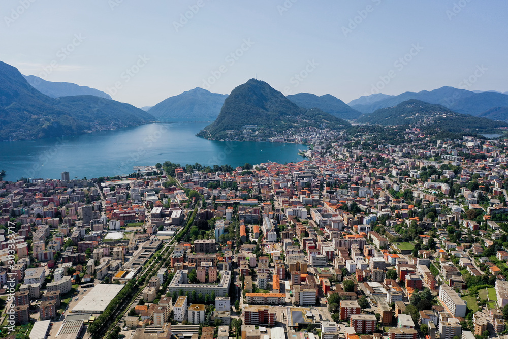 Aerial drone shot of monte salvatore, lugano city and lake in sunny day