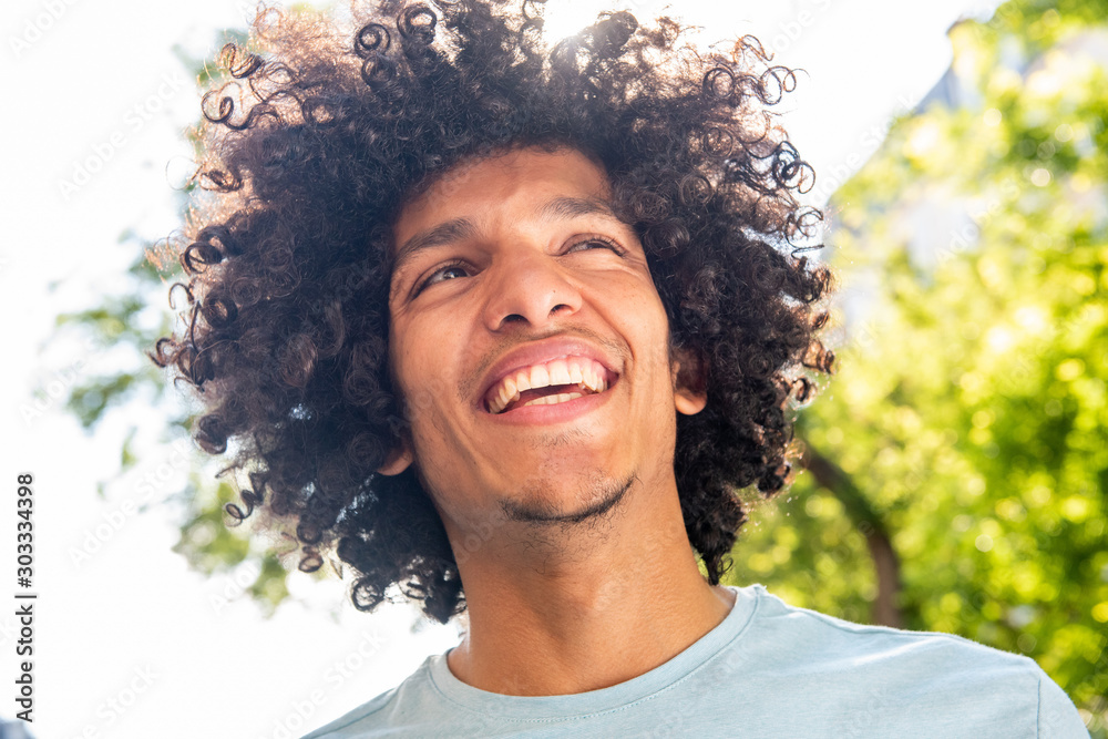 Close up handsome young North African man with afro hair smiling outside - obrazy, fototapety, plakaty 