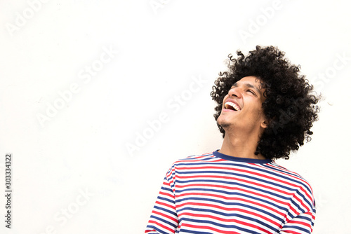 happy young man with afro hair laughing and looking yup against white background