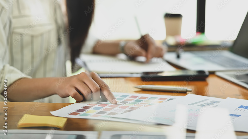 Close-up creative graphic designer with her working on colour selection on paper colour.