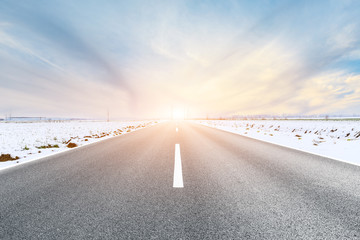Country road and farmland snow scene at sunset
