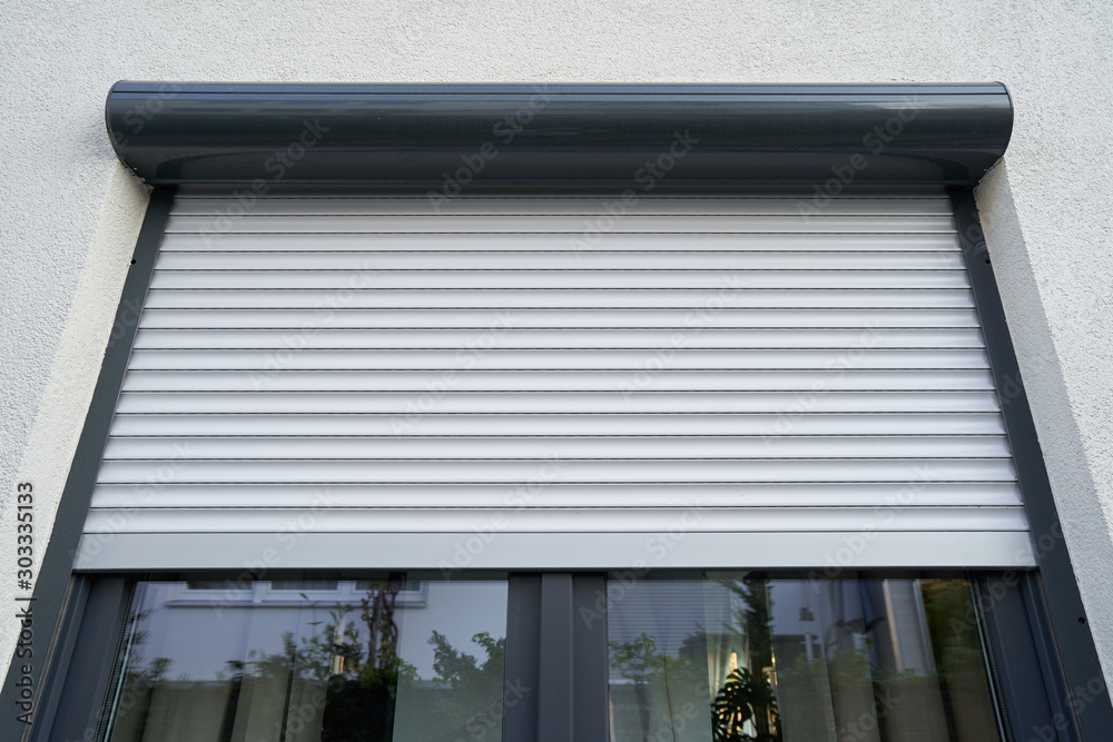 Foto Light roller shutter curtains mounted on a dark window