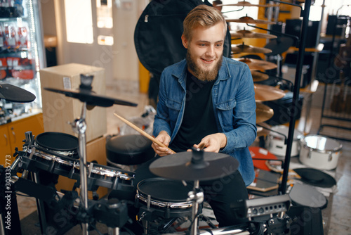 Young musician plays on drum set in music store