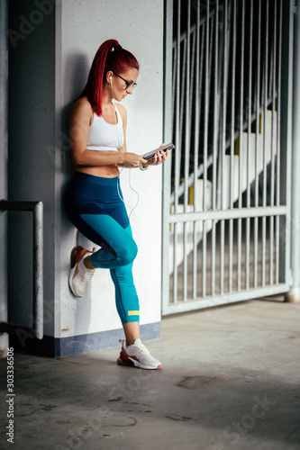 Portait of attractive athletic girl working out and listening to music. Resting after fitness training.