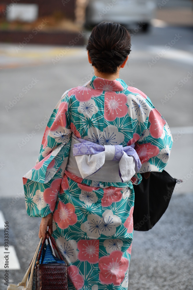 A Japanese woman in a colorful kimono walks on a street in Hiroshima-Japan.