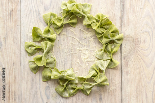 pasta with spinach in the form of bows on wooden table in the shape of circle, wreath photo