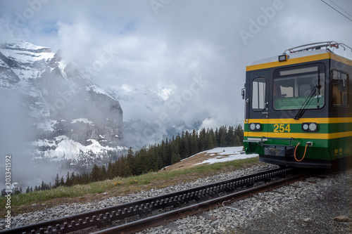 The front of green with yellow hiking train, Jungfrau, with beautiful view of foggy mountain background, copy space, Switzerland