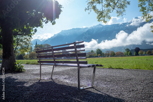 Empty metal bench in public park at Interlaken with mountain and clear blue sky background , copy space