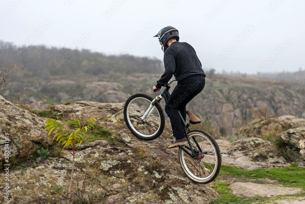 Fototapeta premium Cyclist on a mountain bike is rising up the rocky terrain.