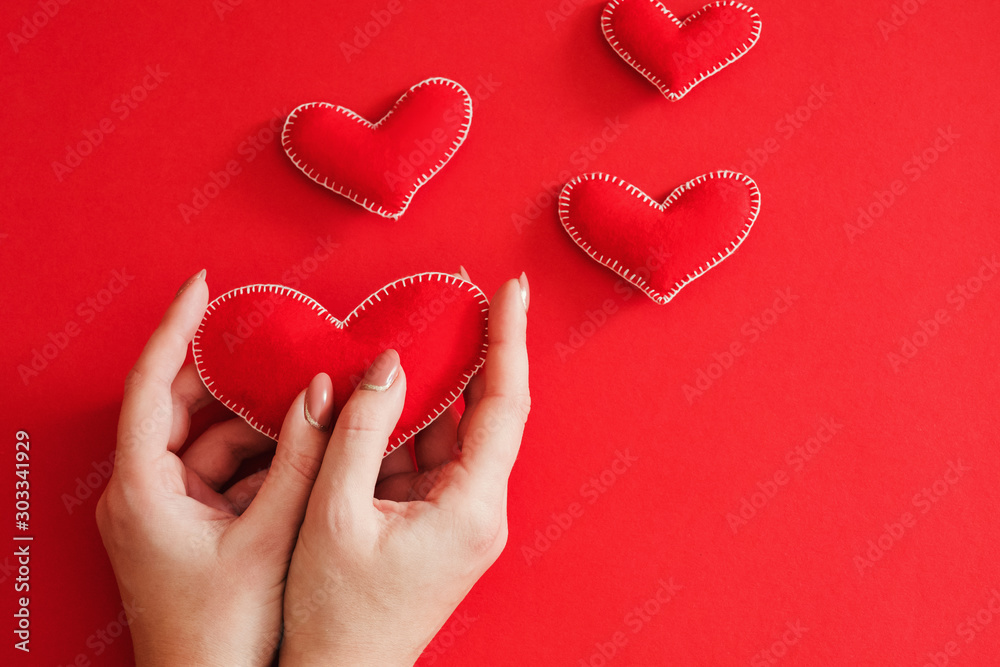 Fototapeta premium Creative Valentine day gift. Flat lay of handmade felt hearts on red background. Copy space.