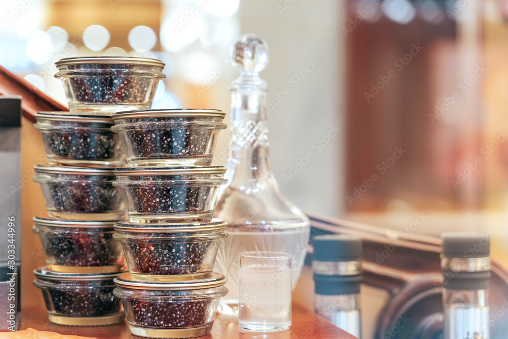 Glass jars with black sturgeon caviar and jar of vodka. Luxurious black caviar. Glass jars with black sturgeon caviar and jar of vodka. Luxurious black caviar.
