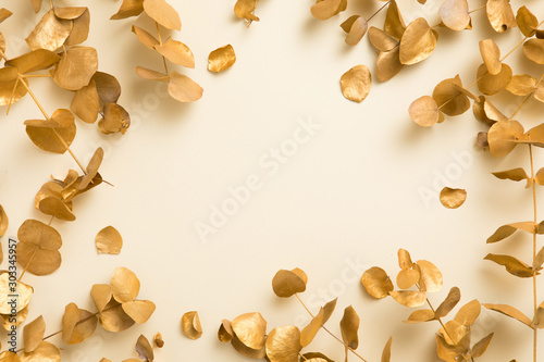 Flat lay of gold leaves eucalyptus populus on beige yellow background. Top vi...