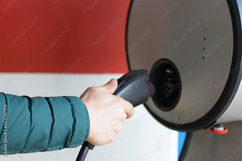 Male hand holds cable for charging an electric car