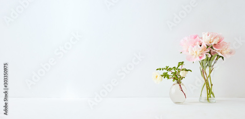 Fototapeta Naklejka Na Ścianę i Meble -  Home interior with decor elements. Pink peonies in a vase and white flowers on a white background